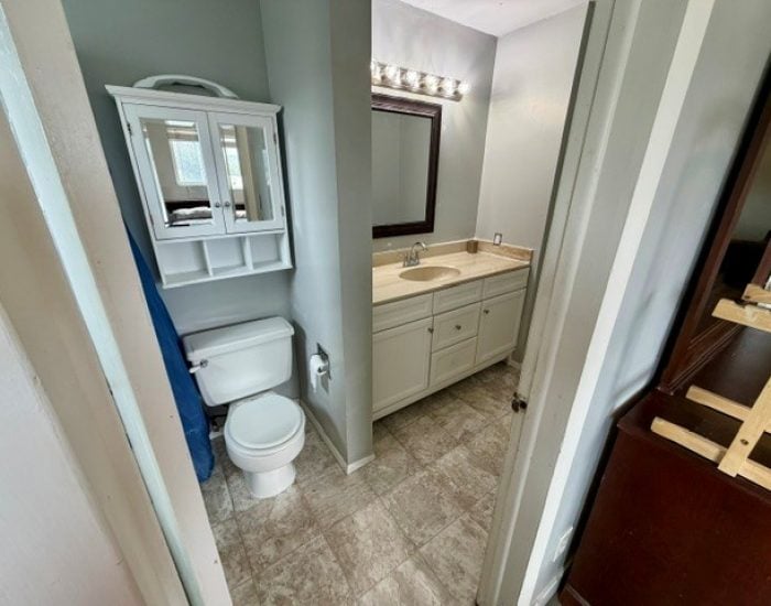 A bathroom with a toilet, a wall-mounted cabinet, and a vanity with a mirror.